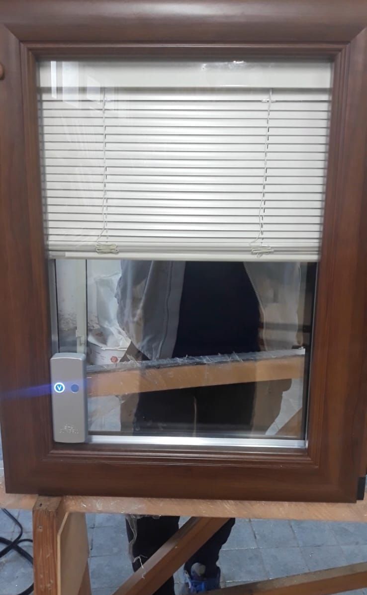 Una finestra con le persiane è appoggiata su un tavolo di legno.