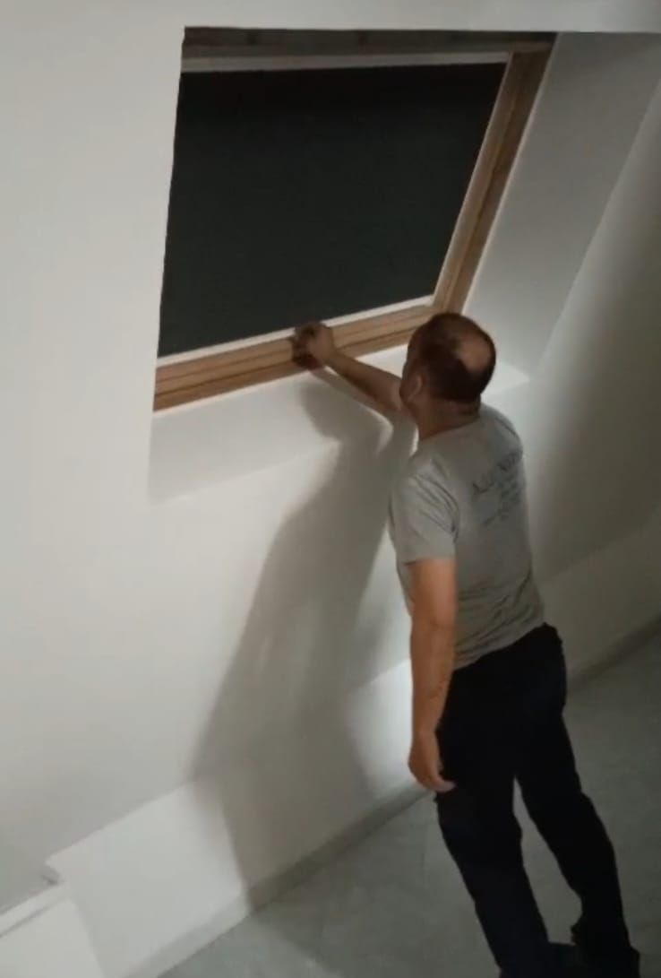 Un uomo è in piedi davanti a una finestra con una tenda nera