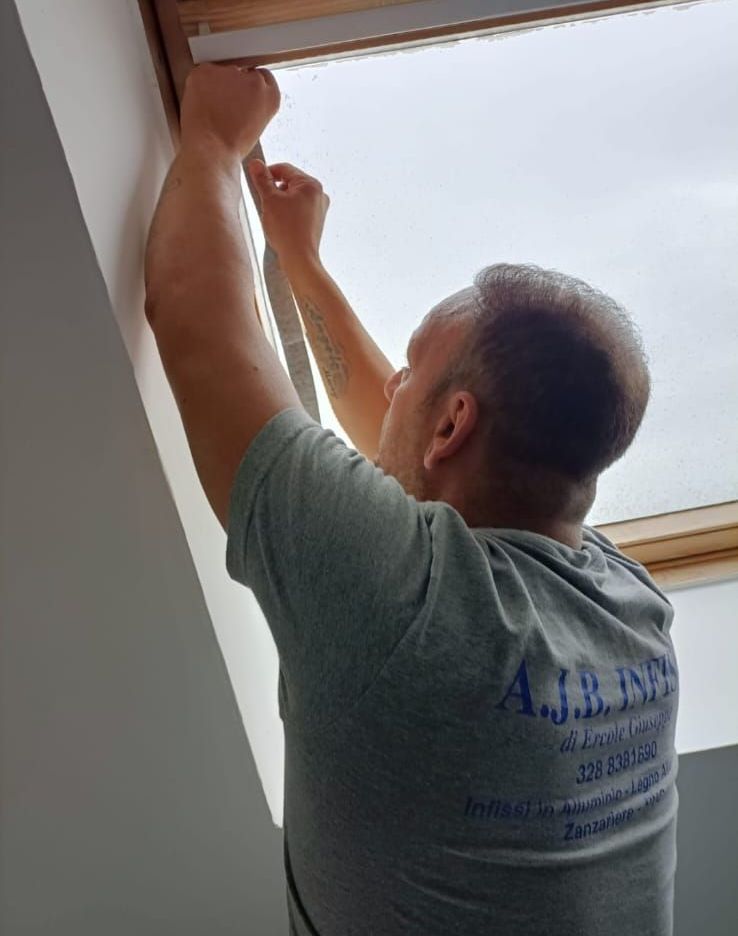 Un uomo sta installando un lucernario in una stanza.