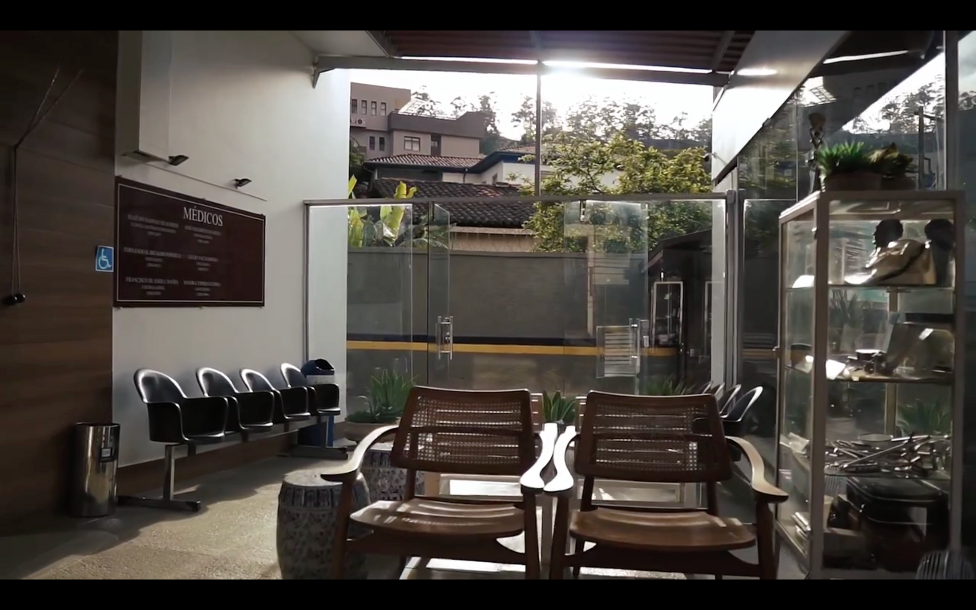 Uma sala de espera com cadeiras de madeira e uma vitrine de vidro.