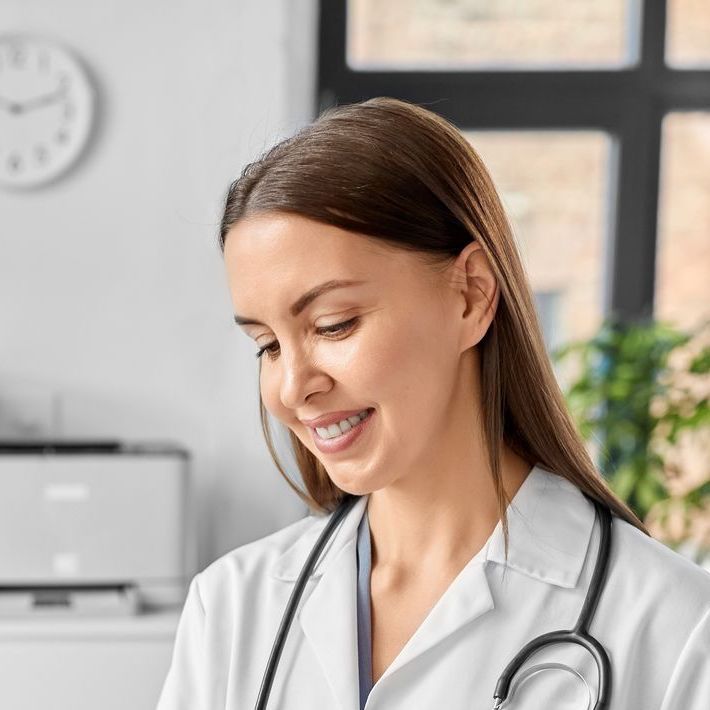 Uma médica com um estetoscópio no pescoço está sorrindo.