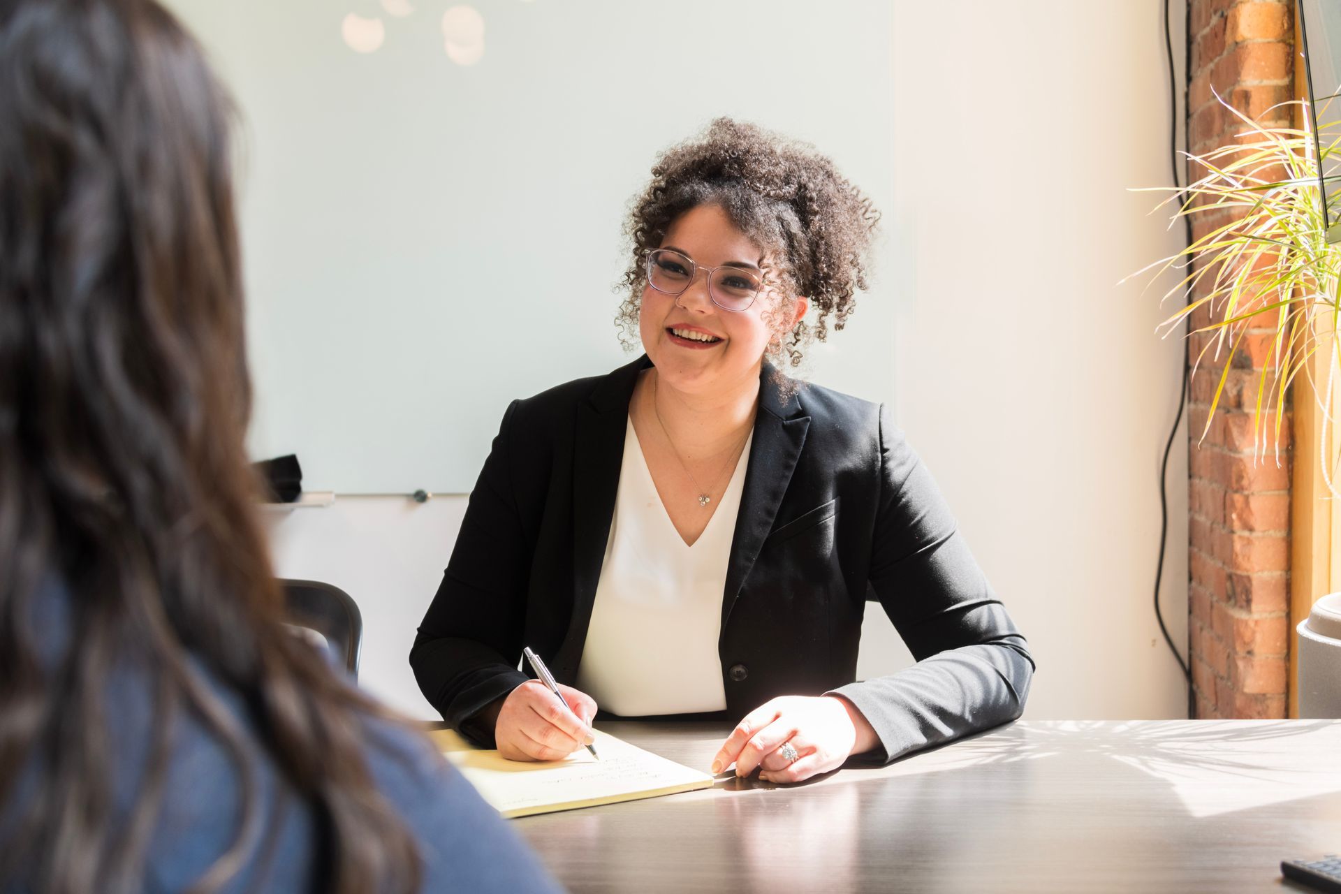 A woman is sitting at a table talking to another woman.