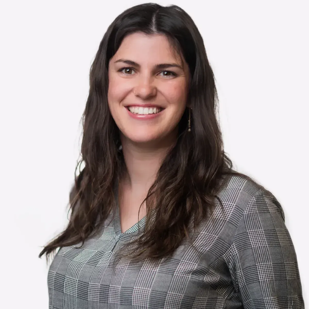 A woman with long hair is smiling and wearing a plaid shirt.