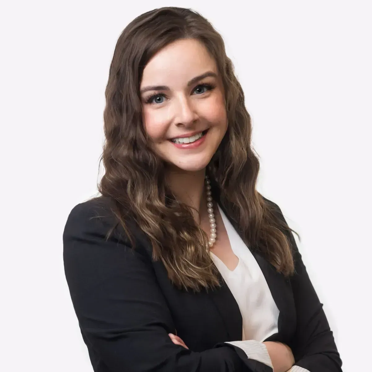 A woman in a black jacket and white shirt is smiling with her arms crossed