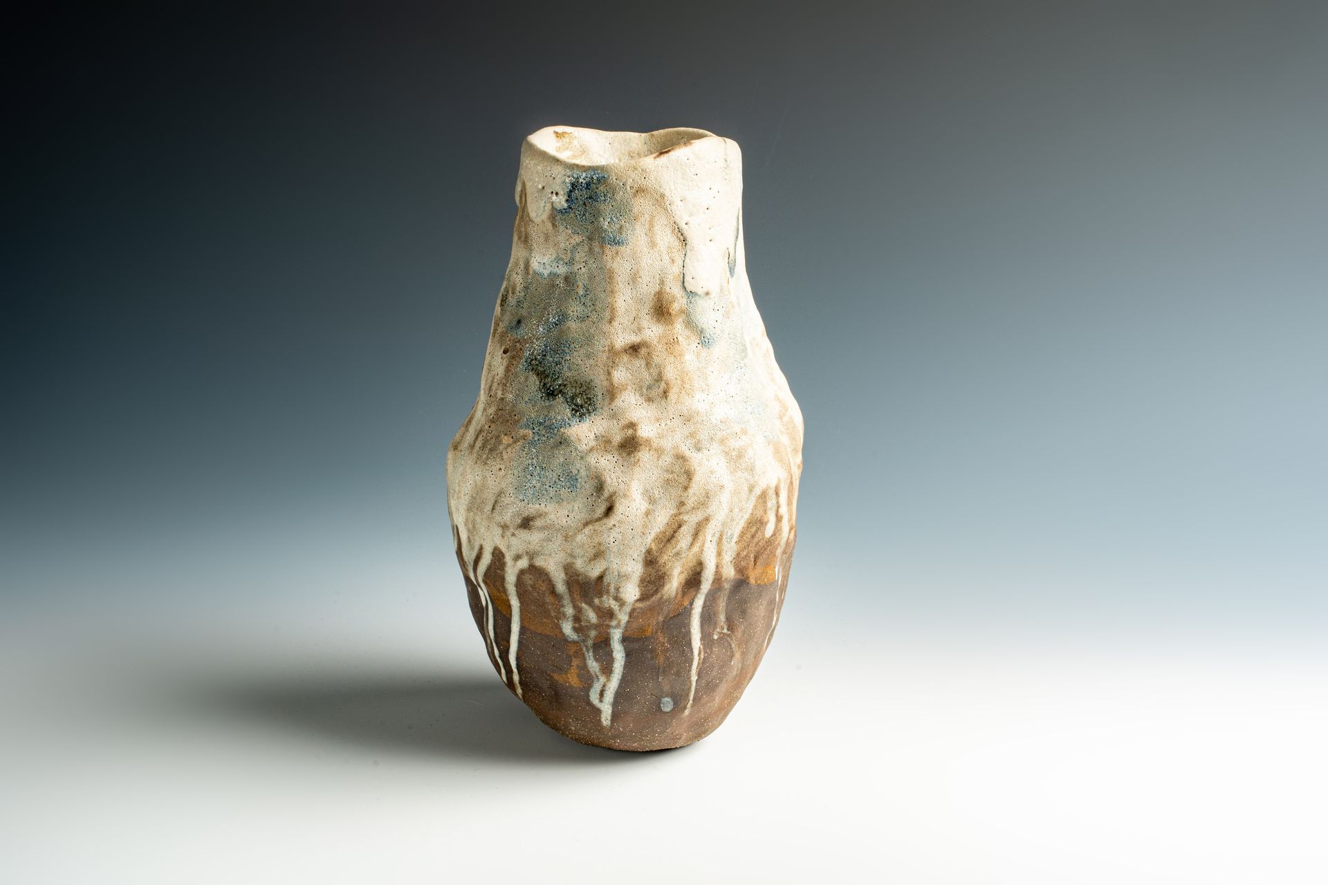 A ceramic vase is sitting on a white table.