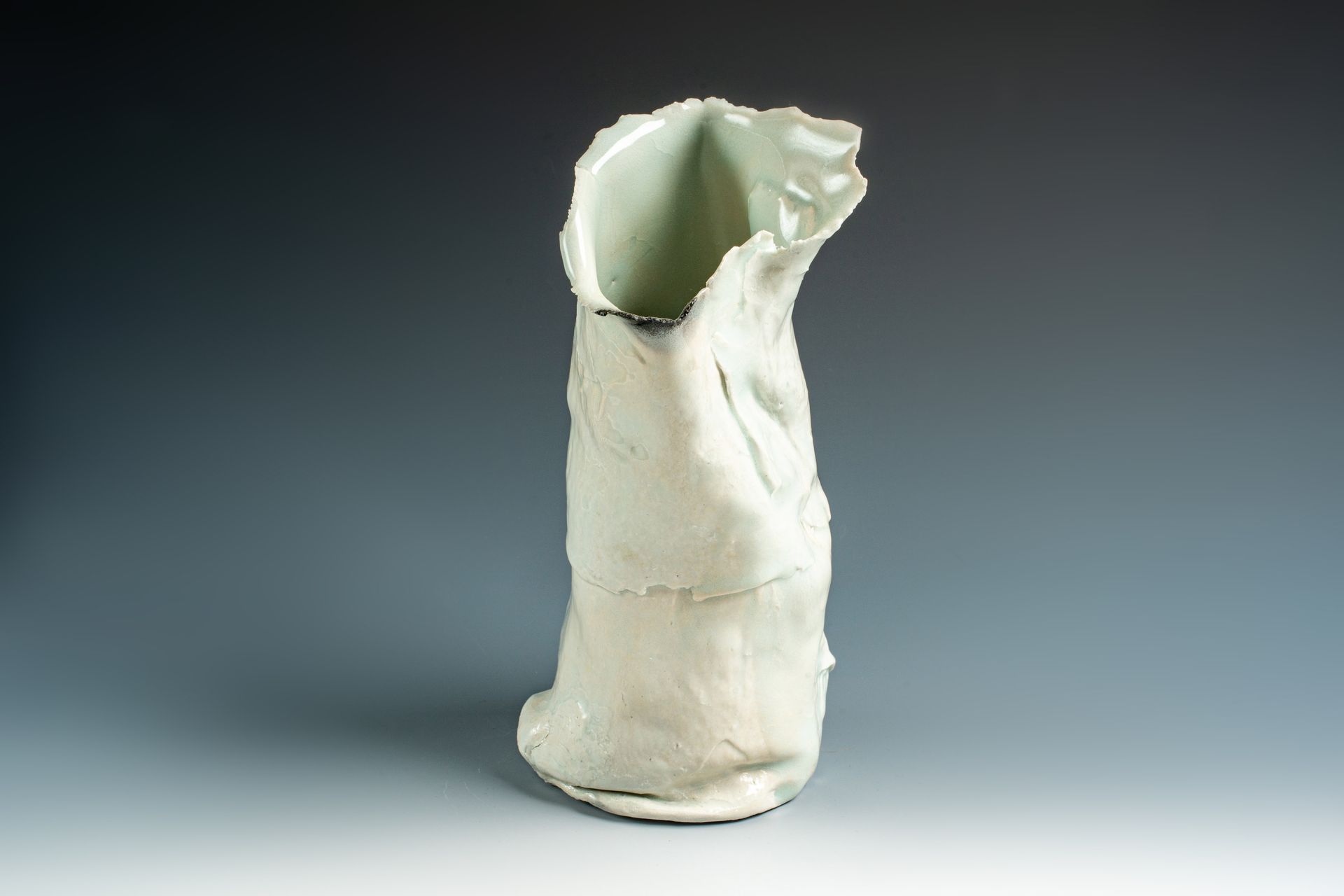 A white vase is sitting on a gray surface