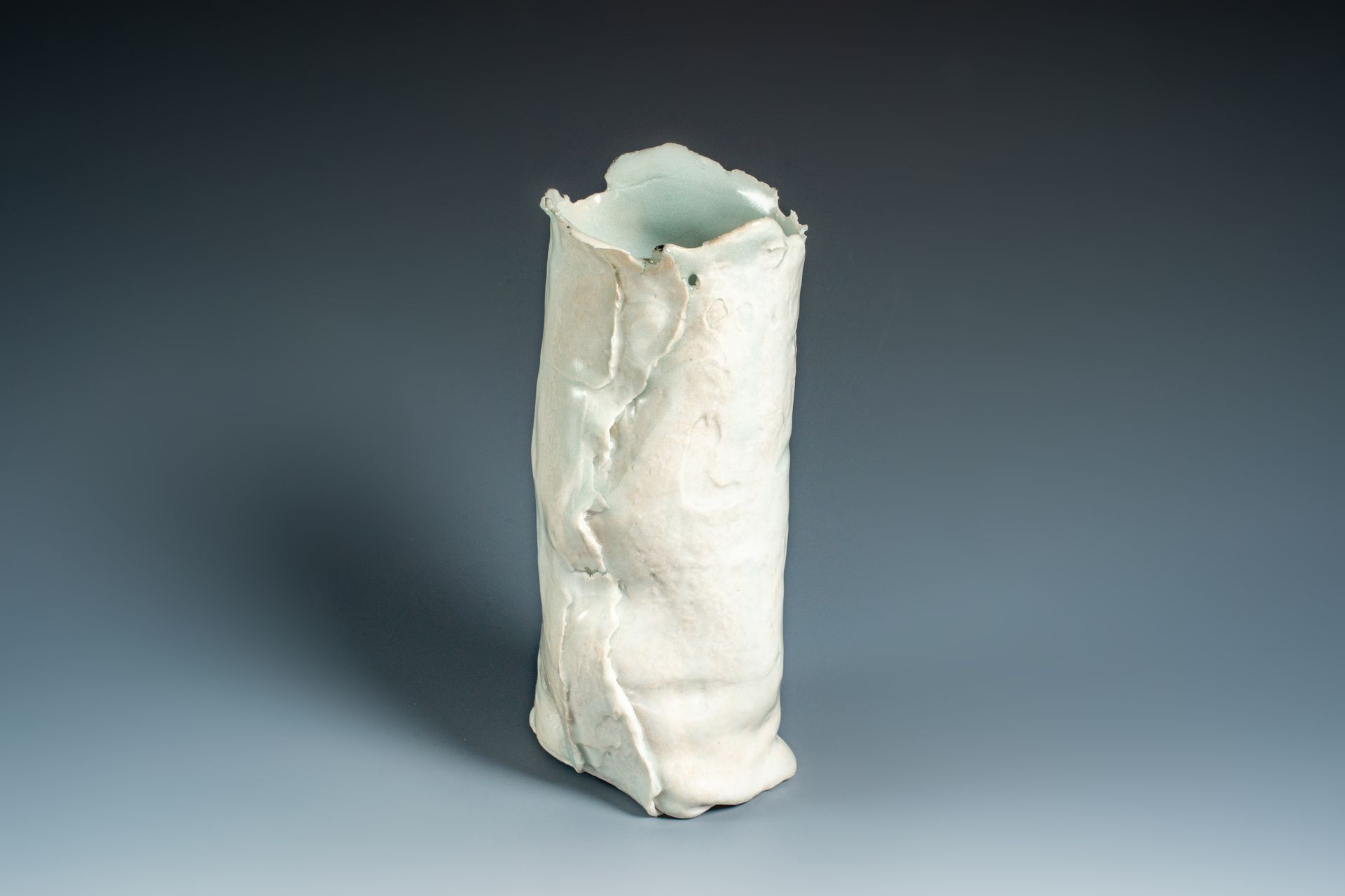 A white vase is sitting on a gray surface.