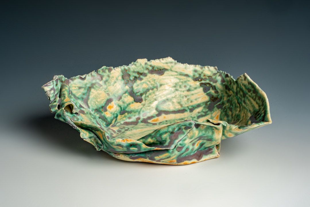 A green and yellow ceramic bowl is sitting on a table.