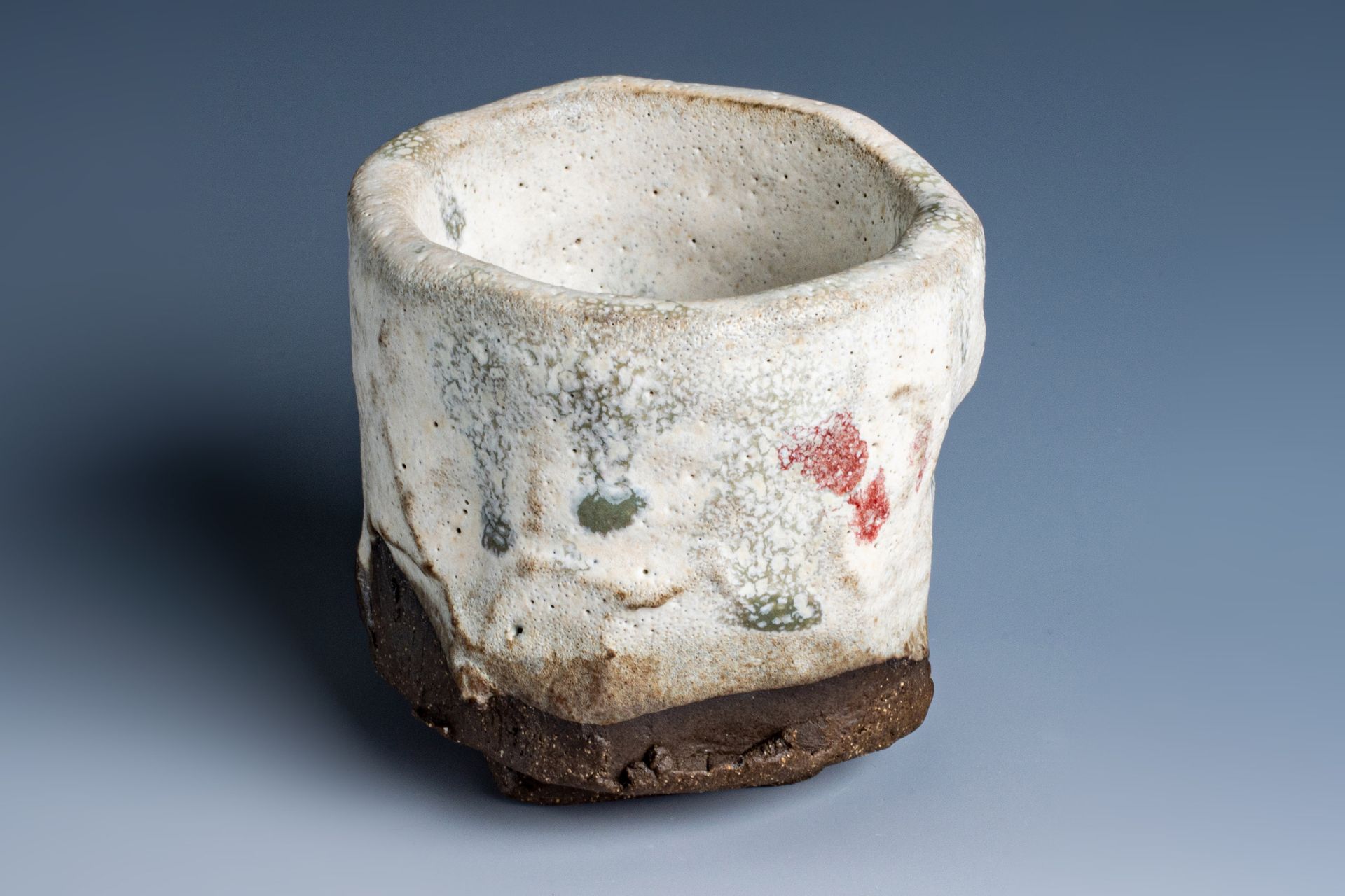 A small white ceramic cup with a brown base is sitting on a blue surface.