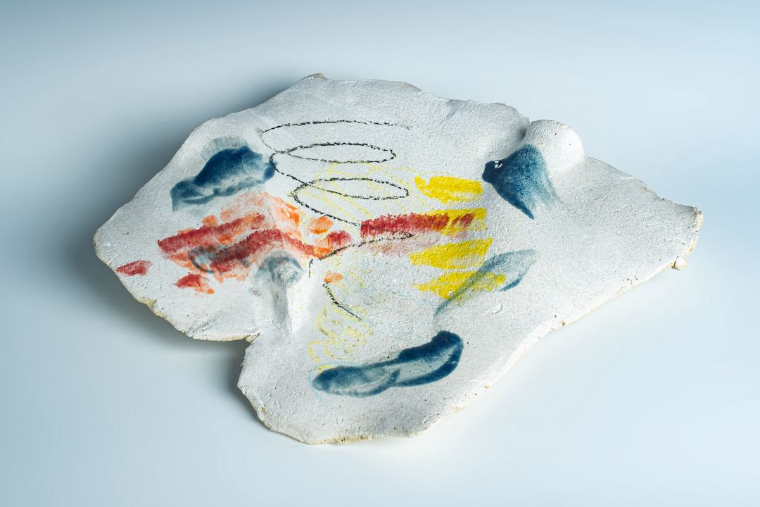 A piece of clay with a colorful design on it is sitting on a white surface.