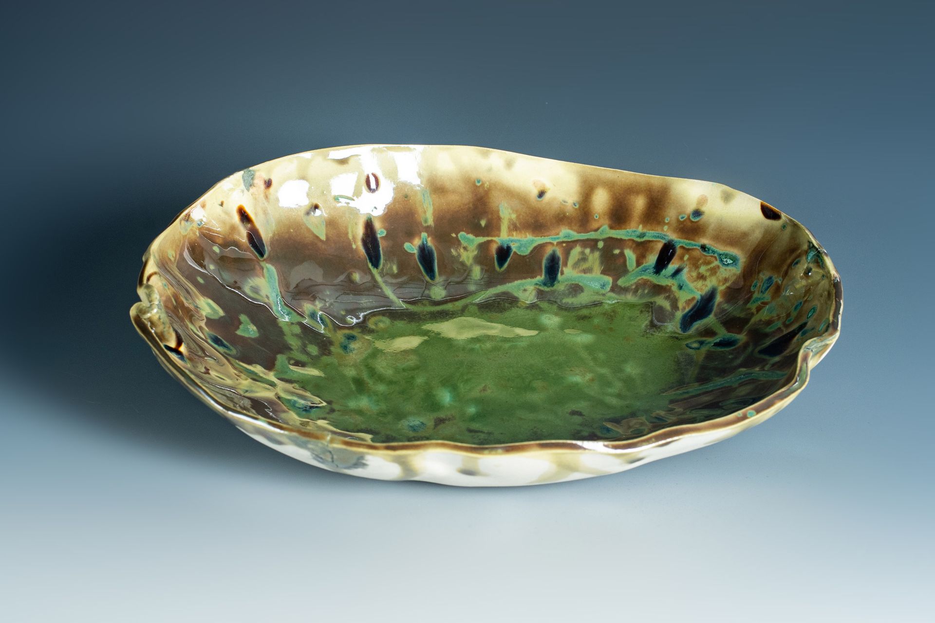 A green and brown bowl is sitting on a table.