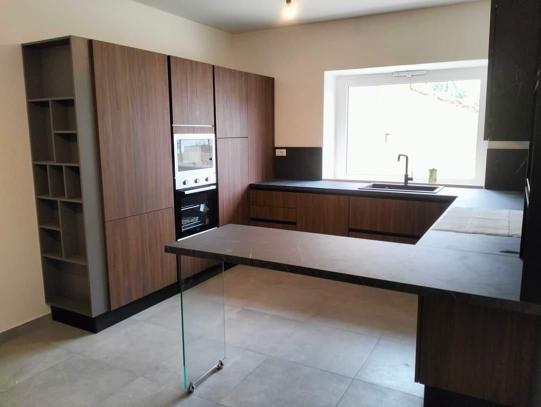 Una cucina con mobili in legno e un piano di lavoro in vetro.