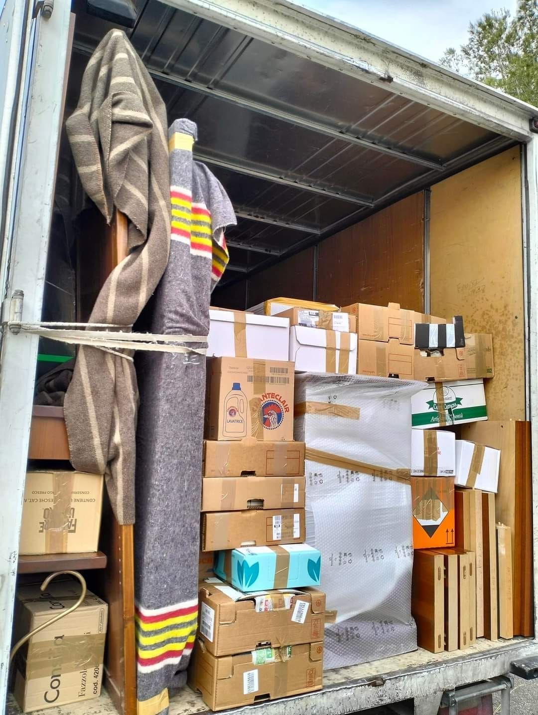 Il retro di un camion in movimento pieno di scatole e una coperta.