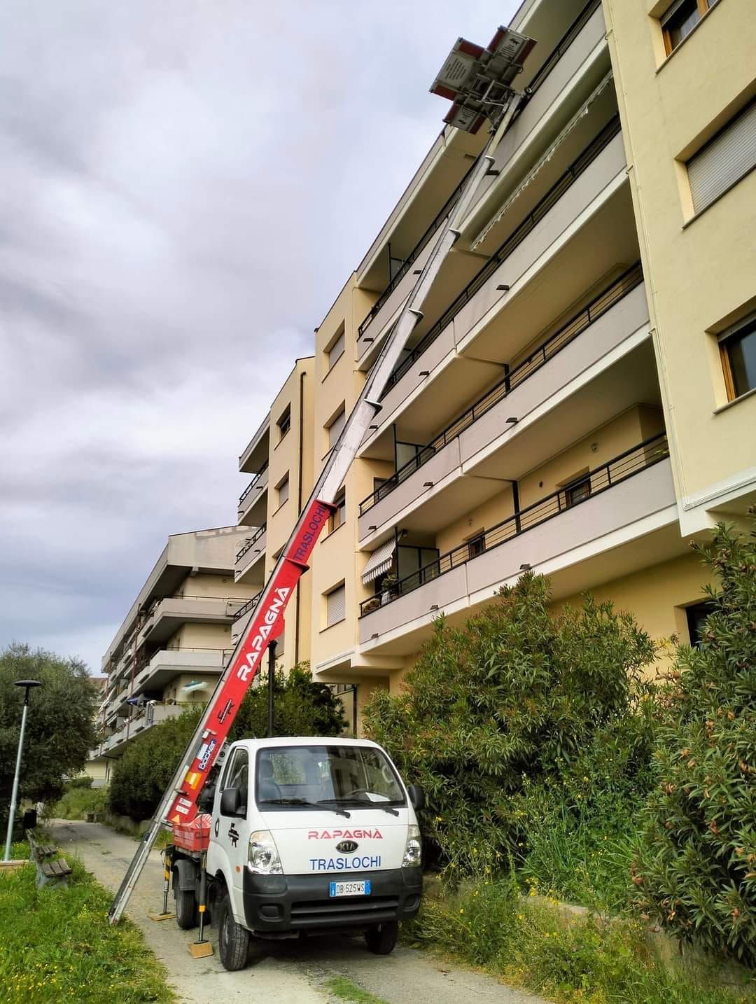 Un camion con una scala attaccata è parcheggiato davanti a un edificio.