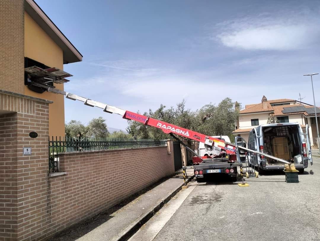 Una gru rossa e bianca è seduta sul ciglio della strada di fronte a un edificio in mattoni.