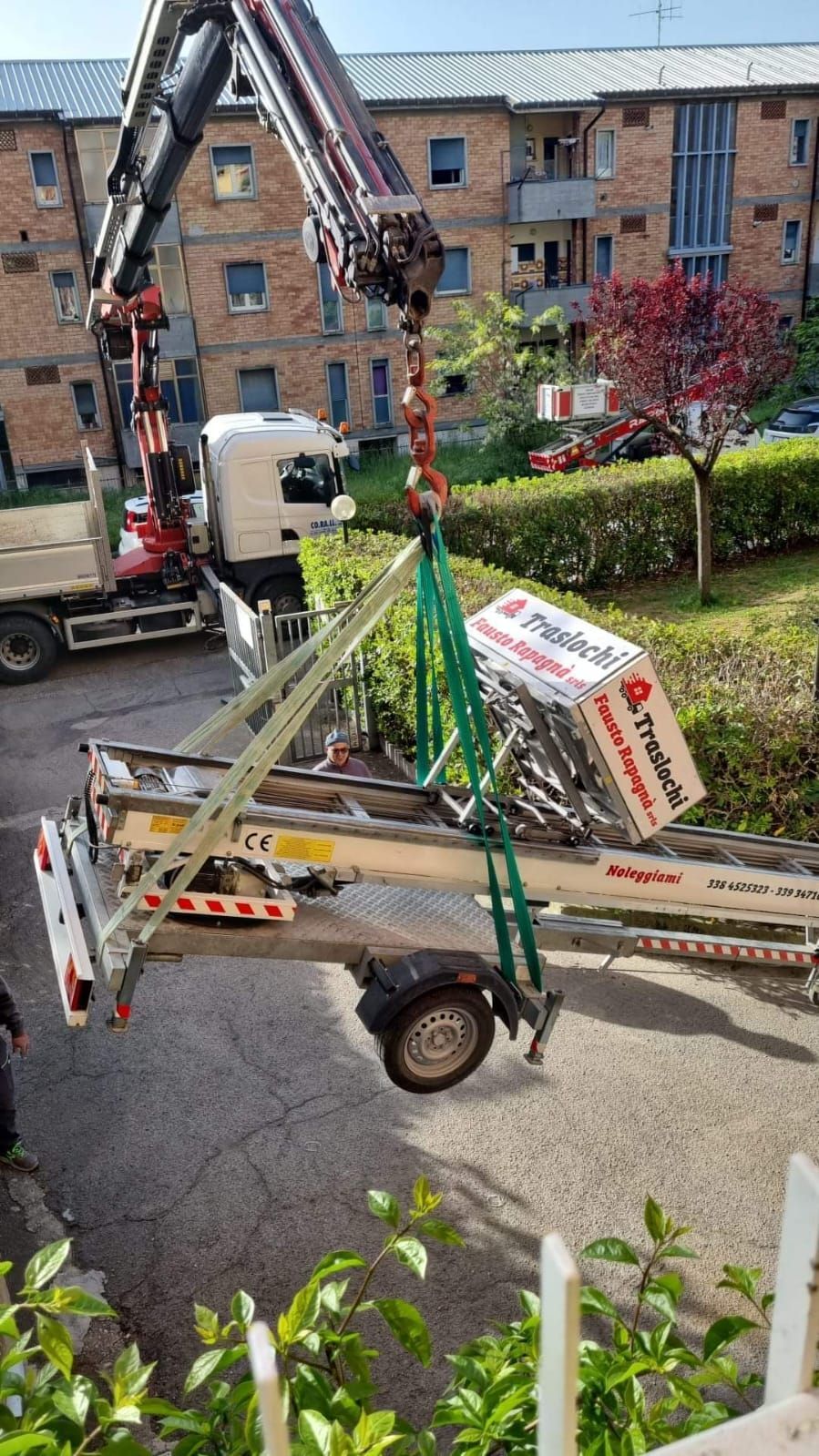 Un camion viene sollevato da una gru su un rimorchio.