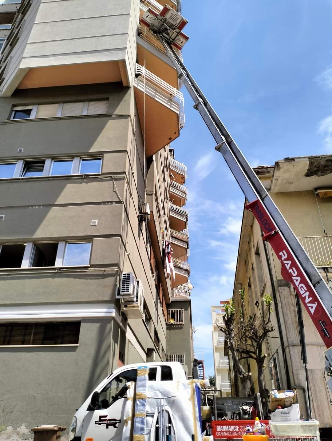 Un camion con una gru agganciata è parcheggiato davanti a un edificio.