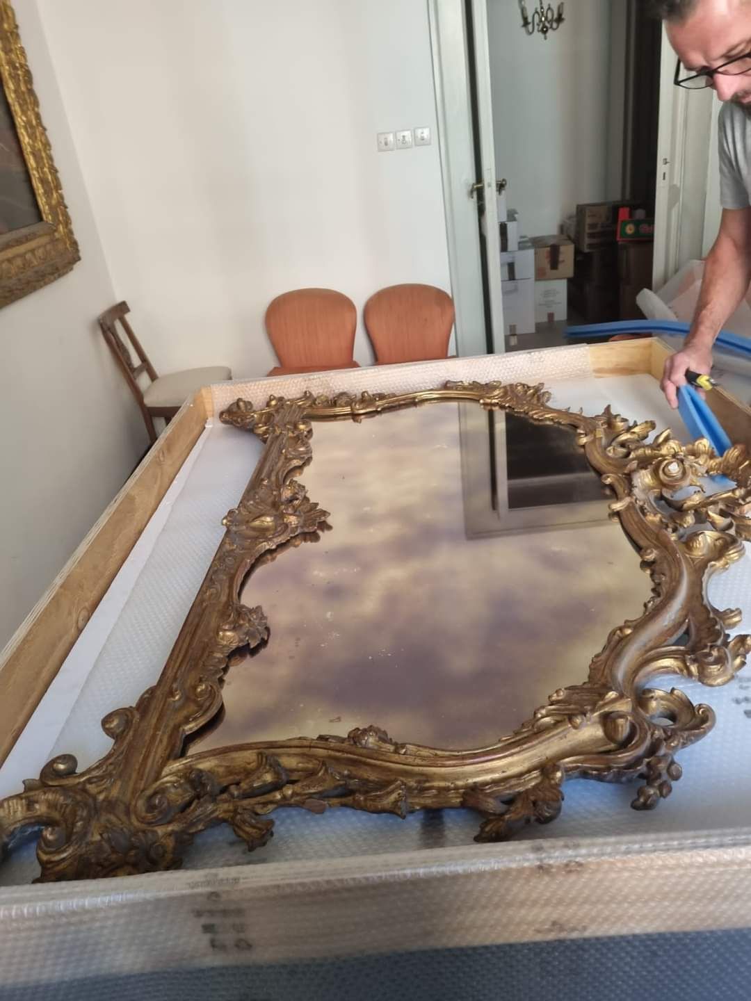 Un uomo sta misurando un grande specchio in una scatola di legno