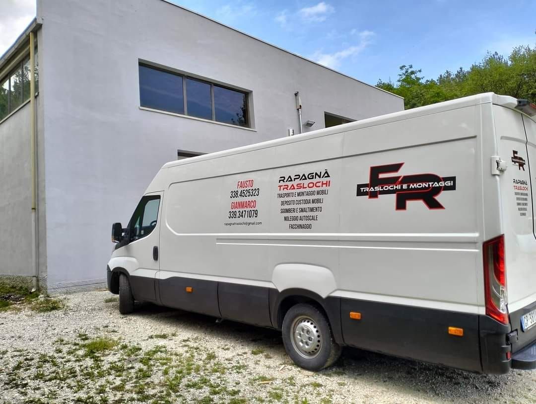 Un furgone bianco con la lettera f sulla fiancata è parcheggiato davanti a un edificio.