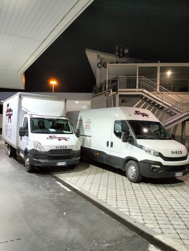 Due furgoni bianchi sono parcheggiati uno accanto all'altro in un parcheggio di notte.