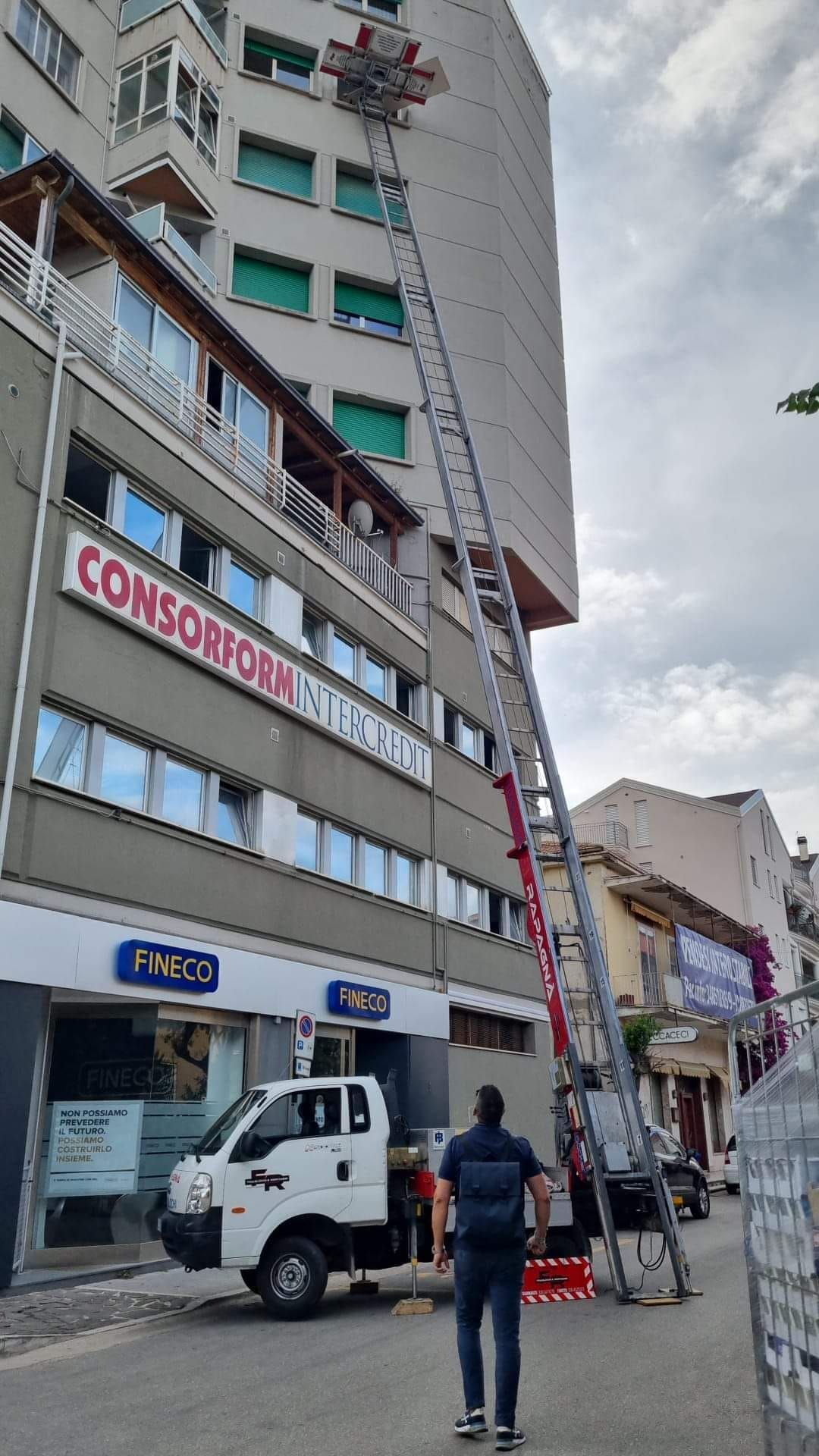 Un uomo è in piedi davanti a un camion bianco a cui è attaccata una scala.