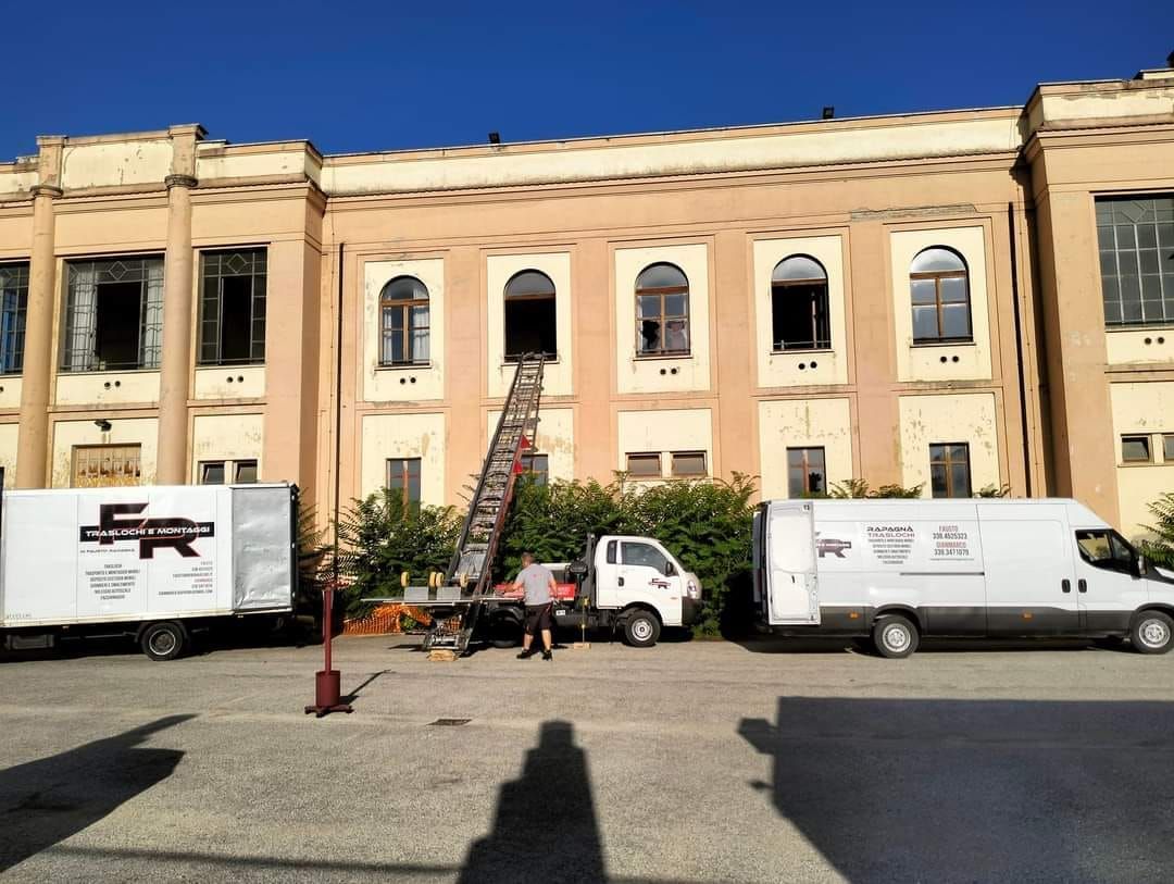 Due furgoni bianchi sono parcheggiati davanti a un grande edificio