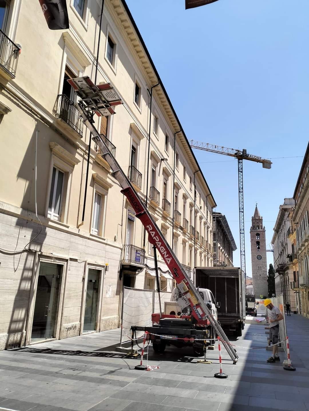 Un camion con una gru agganciata è parcheggiato davanti a un edificio.
