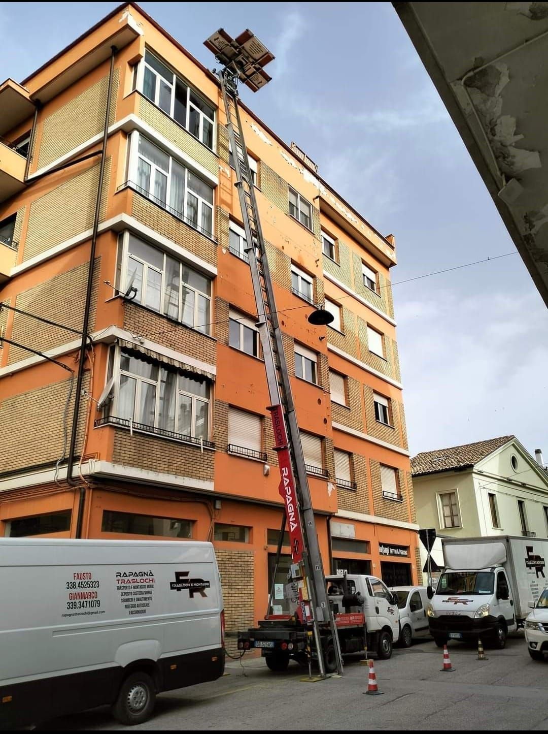 Un furgone bianco è parcheggiato davanti a un edificio arancione