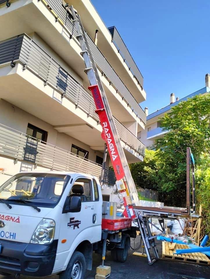 Un camion bianco con una gru attaccata è parcheggiato davanti a un edificio.