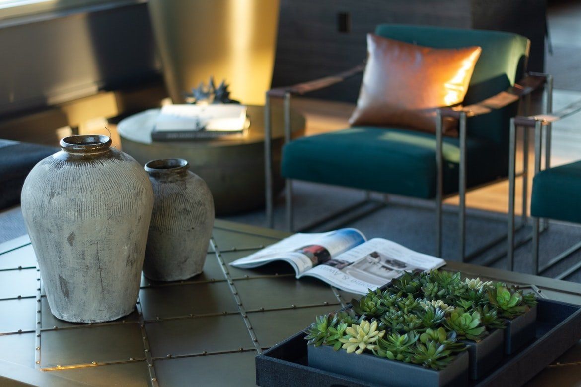 Modern patio with green chair, decorative vases, open magazine, and a planter on a tiled table.