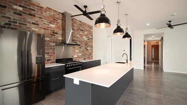 Kitchen With A Large Island, Stainless Steel Appliances, And A Brick Wall — DAV Electrical in Kirwan QLD