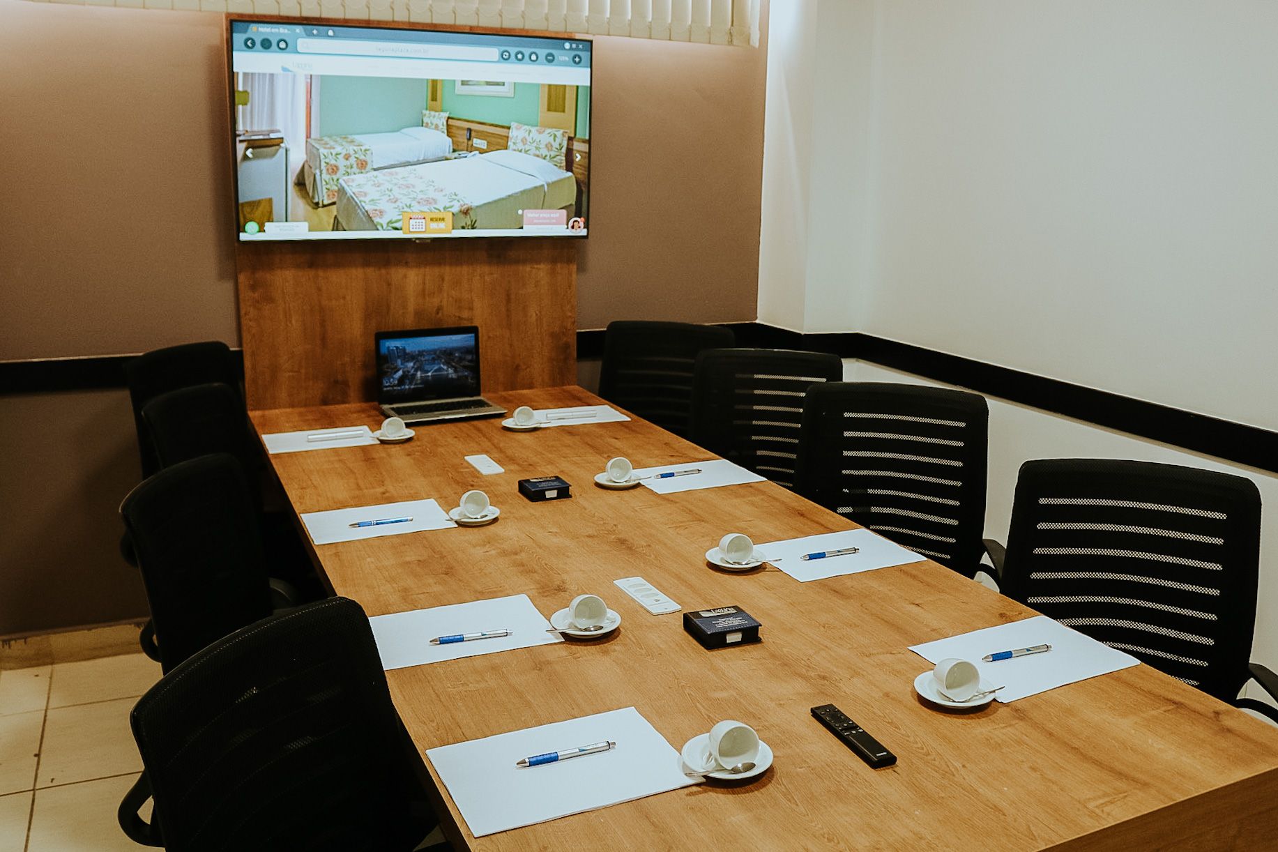 Uma sala de conferências com uma mesa longa, cadeiras e uma TV de tela plana.