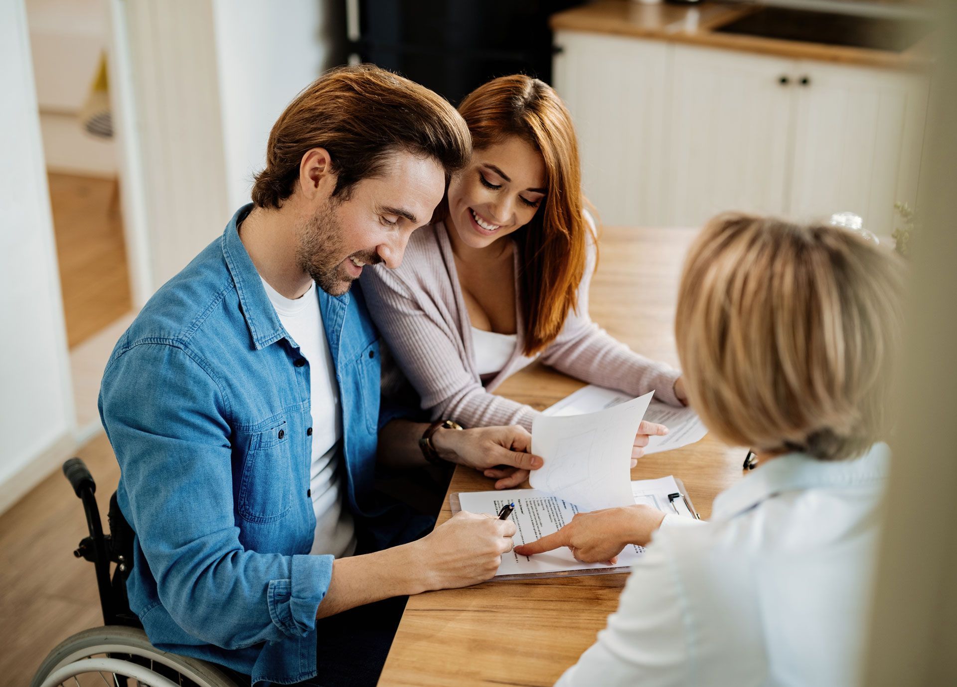 Couple in discussion with a financial advisor at a table; man uses wheelchair.