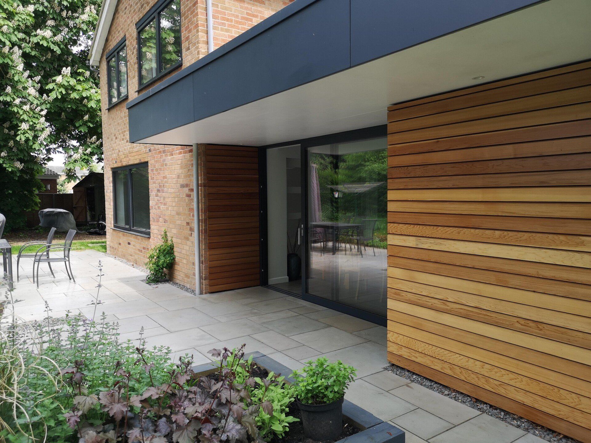 A brick house with a wooden siding and a patio in front of it.