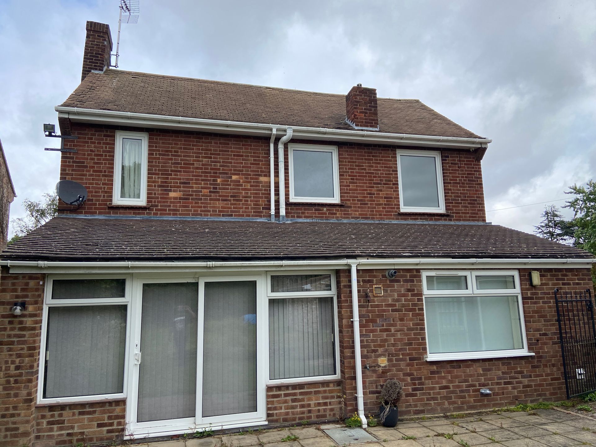 A brick house with white windows and a brown roof.