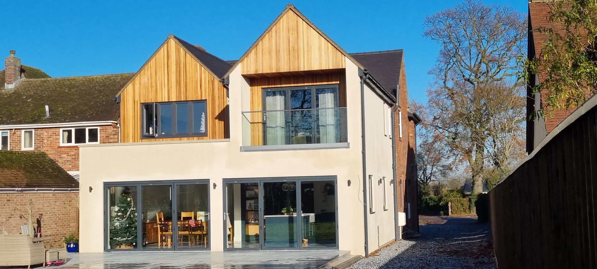 The back of a house with a lot of windows and a wooden roof.