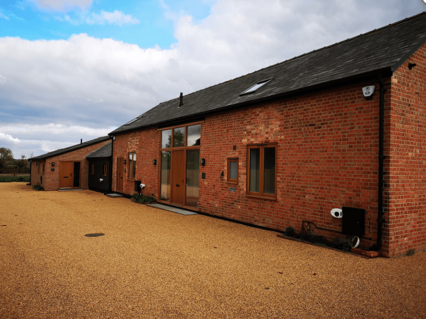 A large brick building with a gravel driveway in front of it.