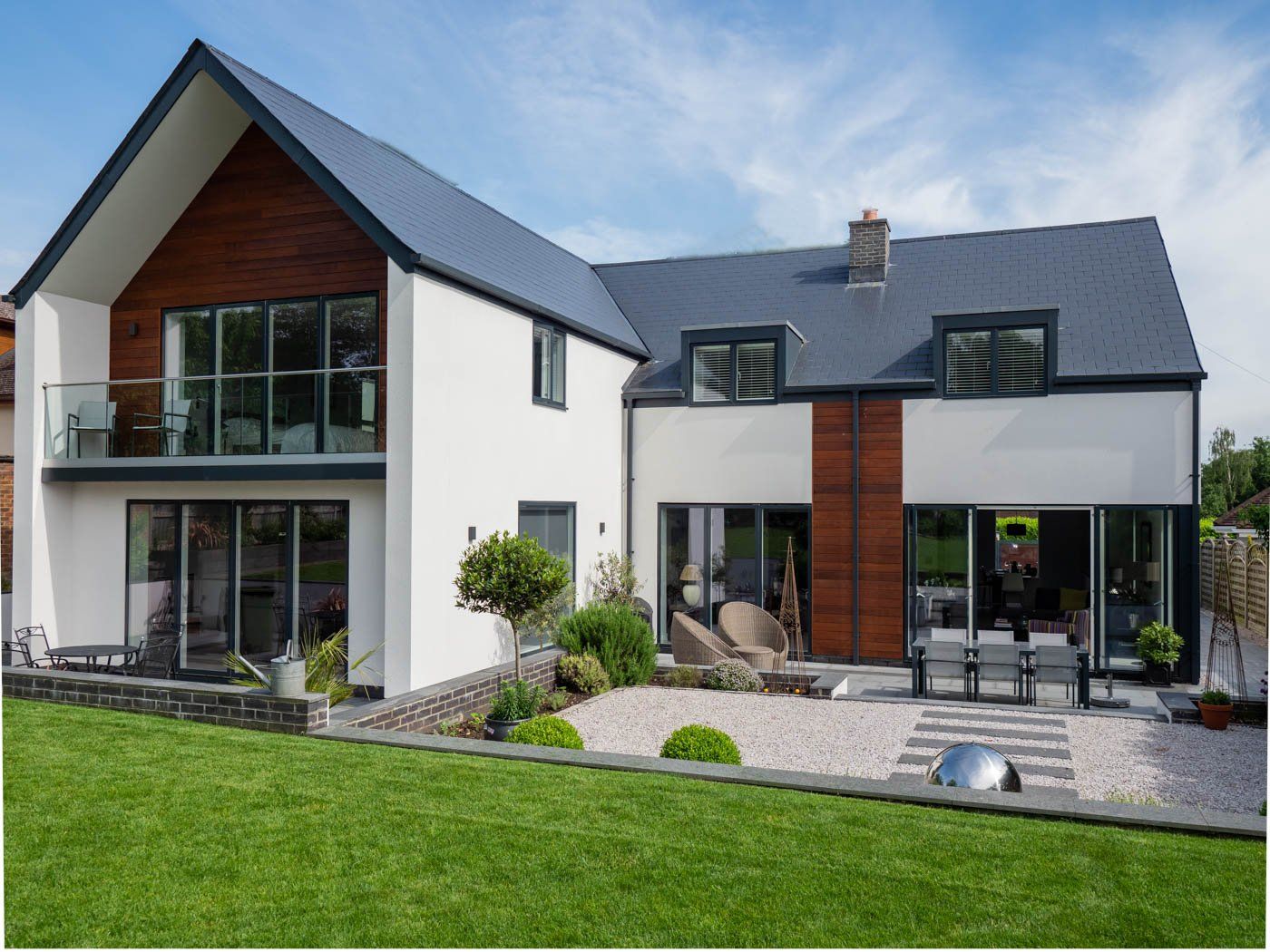 A large white house with a black roof is sitting on top of a lush green lawn.