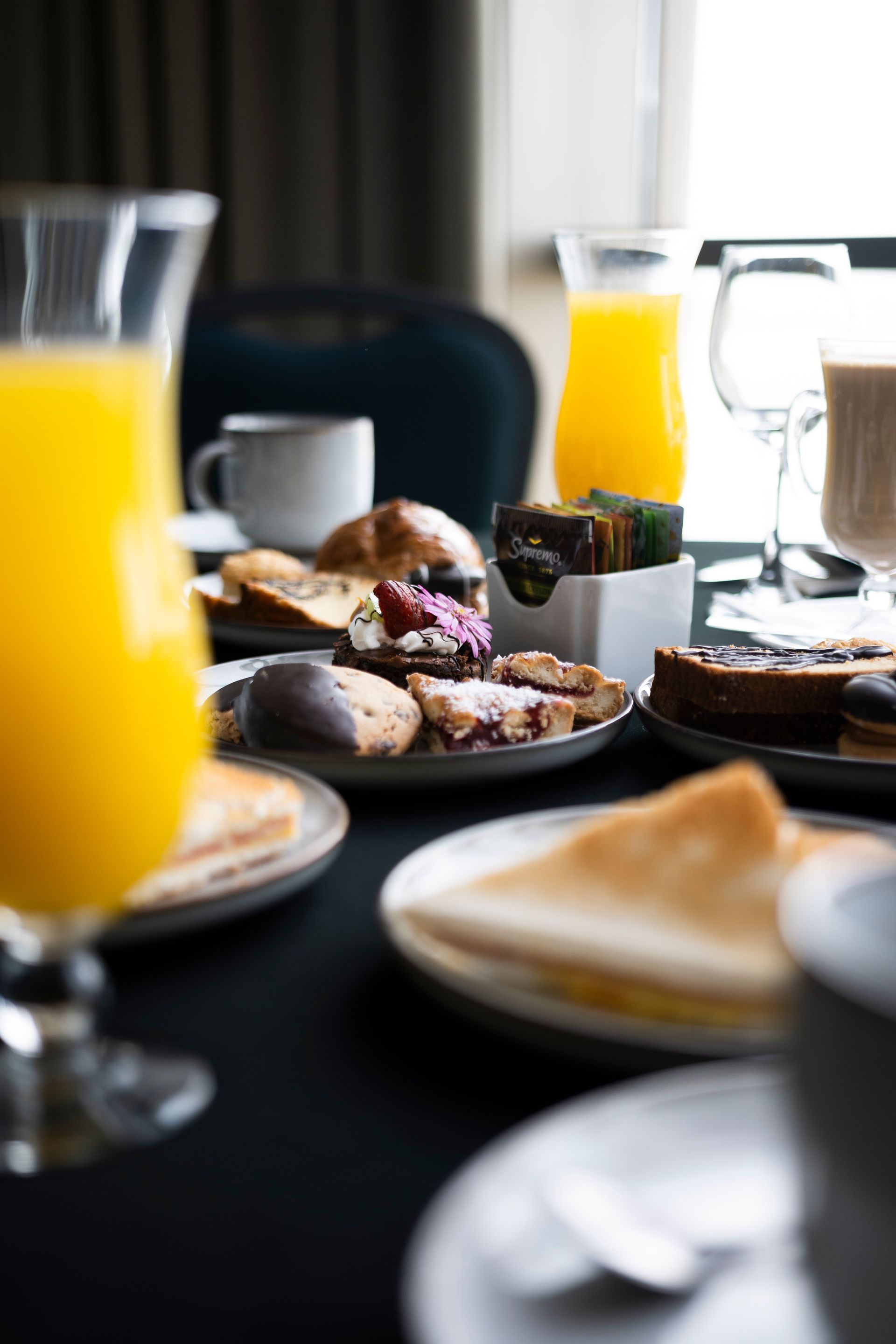 Una mesa cubierta con platos de comida y un vaso de zumo de naranja.