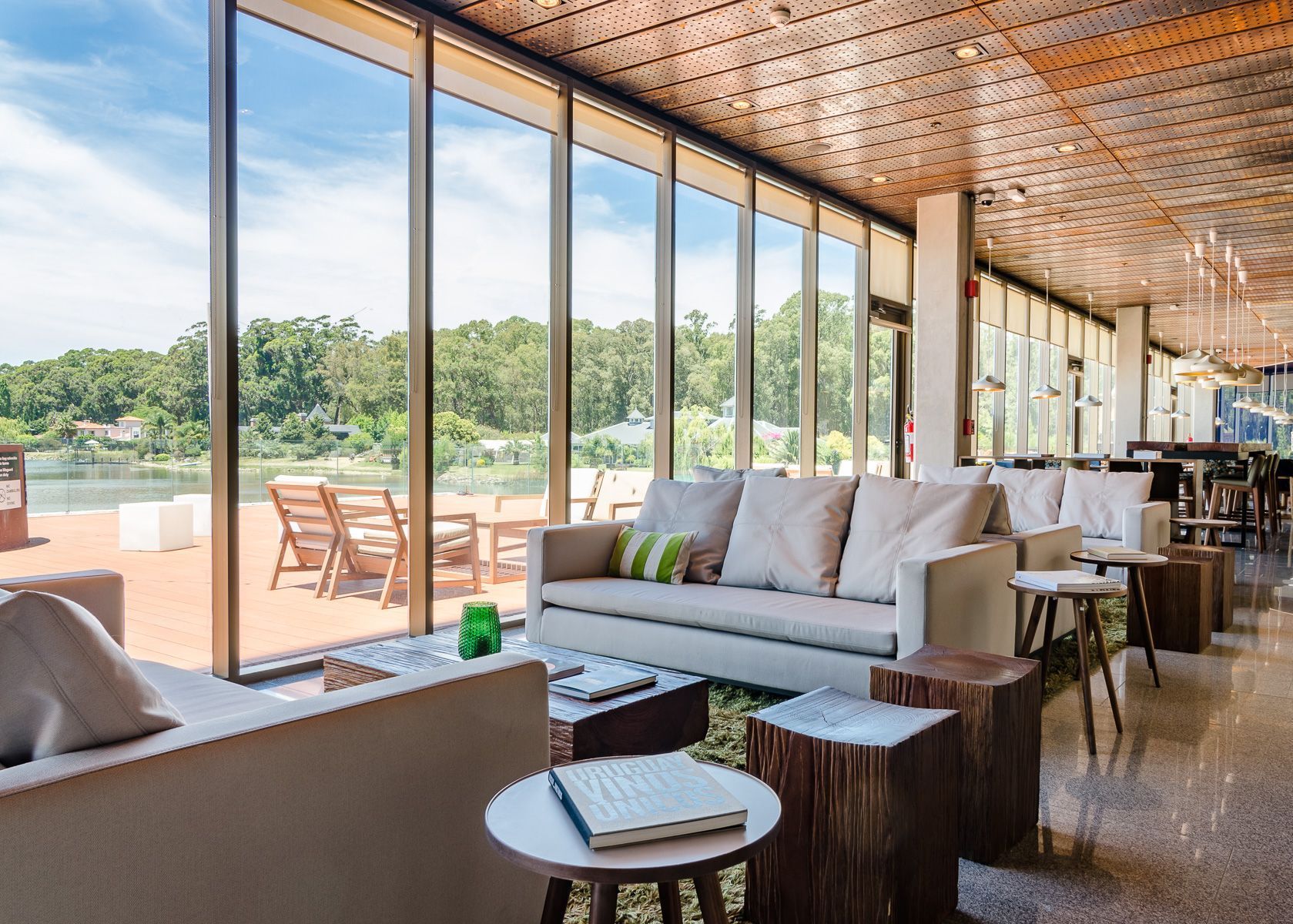 Sala de estar con sofá, sillas, mesas y vista a un lago.