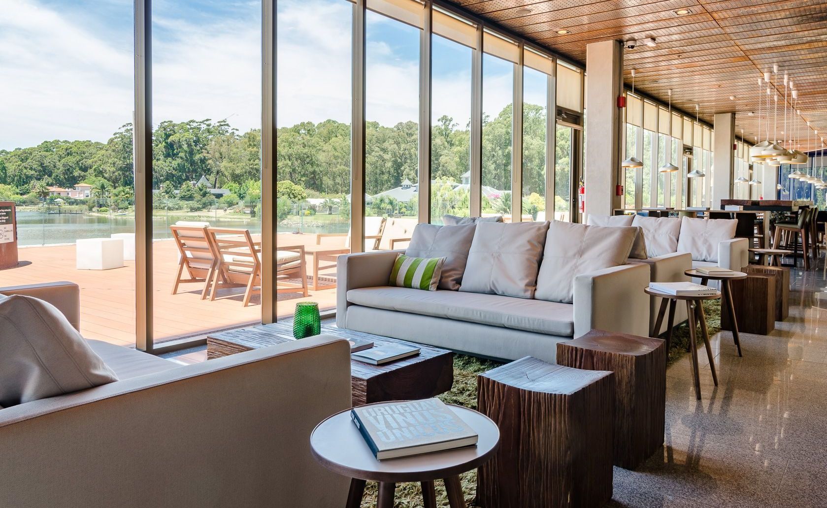 Sala de estar con sofá, sillas, mesas y vista a un lago.