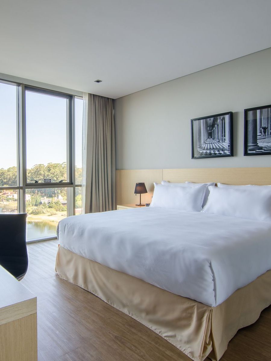 Una habitación de hotel con una cama king size y un gran ventanal.