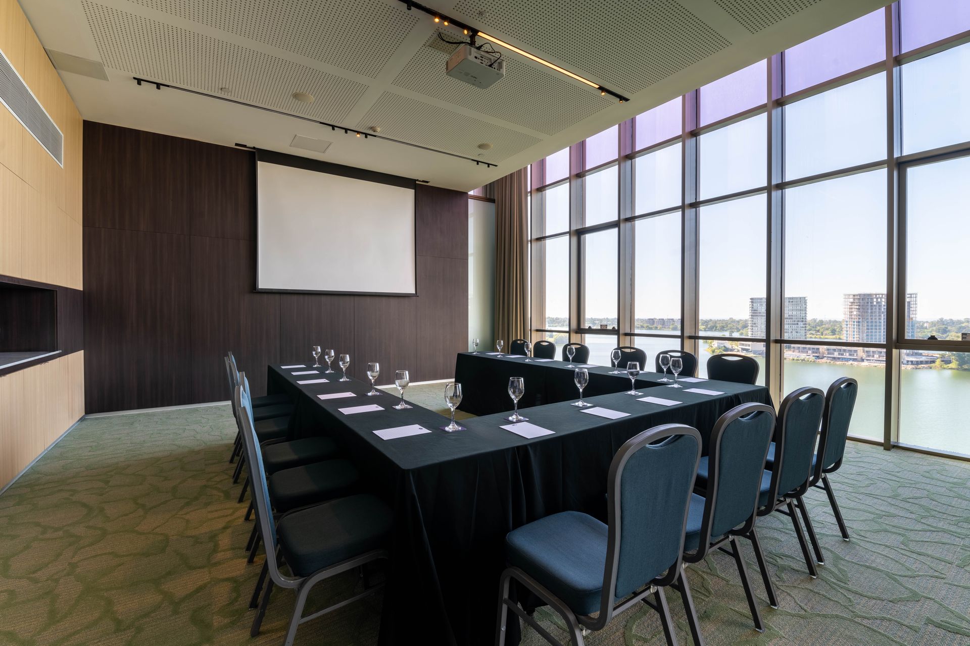 Una sala de conferencias con una mesa larga y sillas preparadas para una reunión.