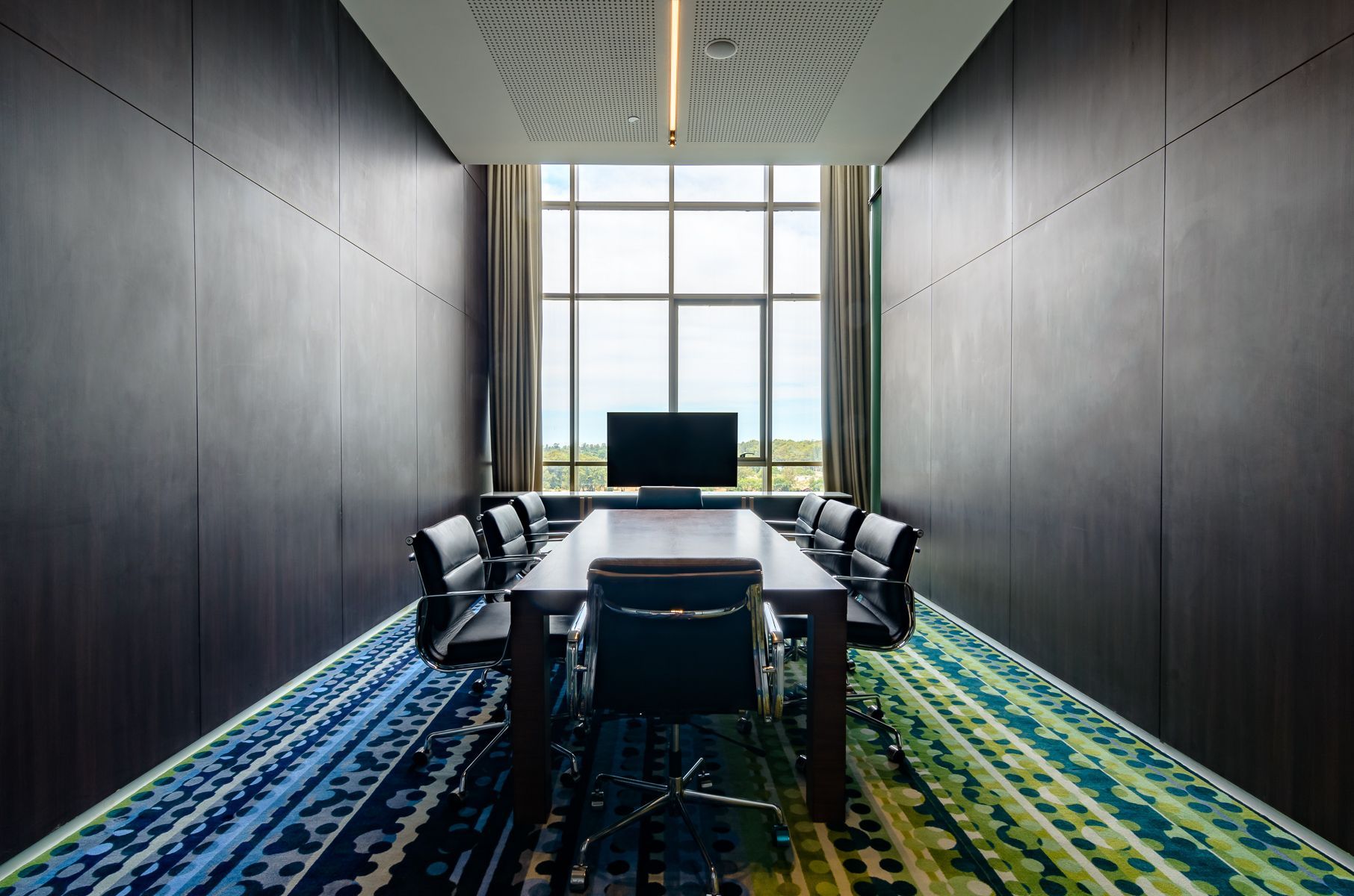 Sala de conferencias con una mesa larga, sillas y un gran ventanal.