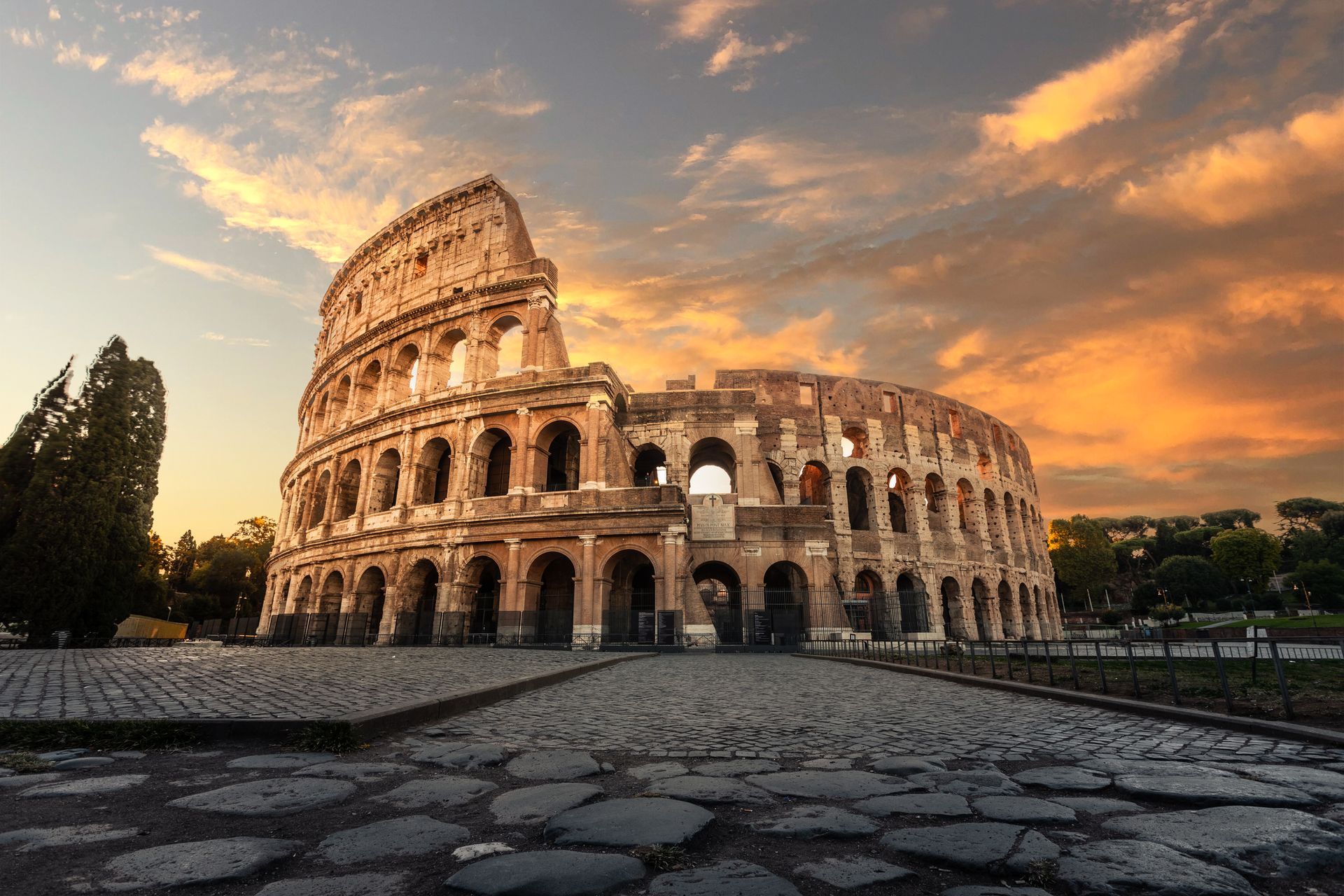 the colosseum in rome is a large building with a sunset in the background .