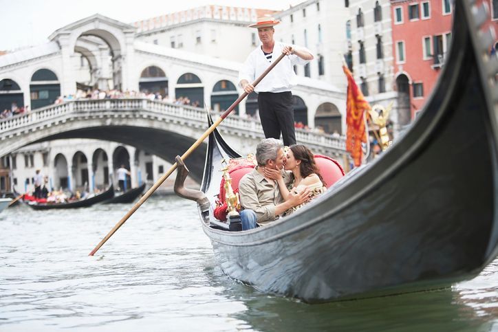 a man and woman are kissing in a gondola in venice .