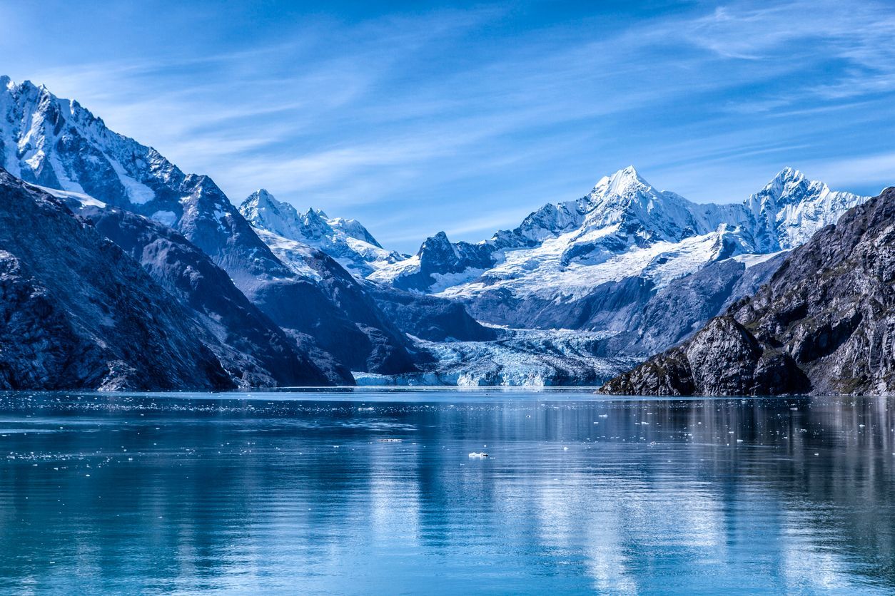 a lake surrounded by snow covered mountains and a glacier .