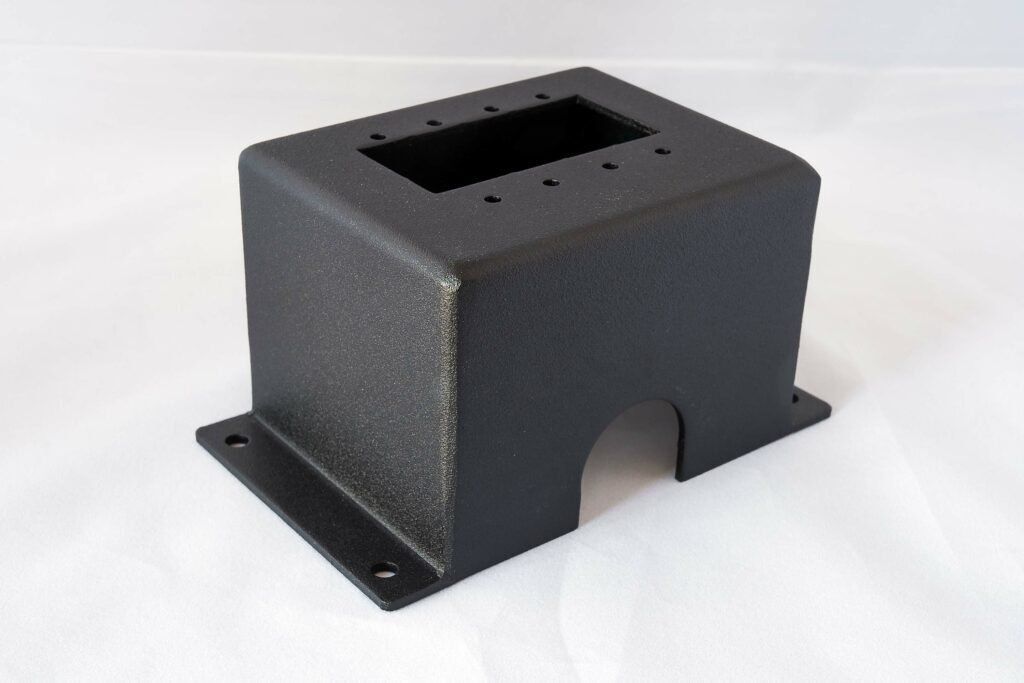 A black box with holes in it is sitting on a white surface