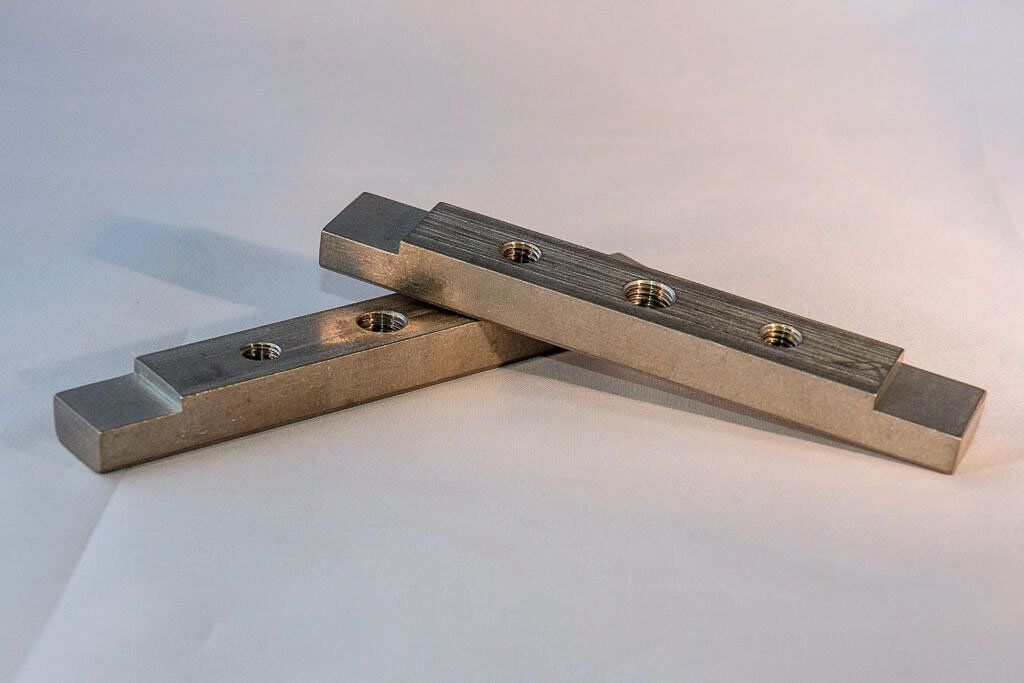 Two metal bars are stacked on top of each other on a white surface.