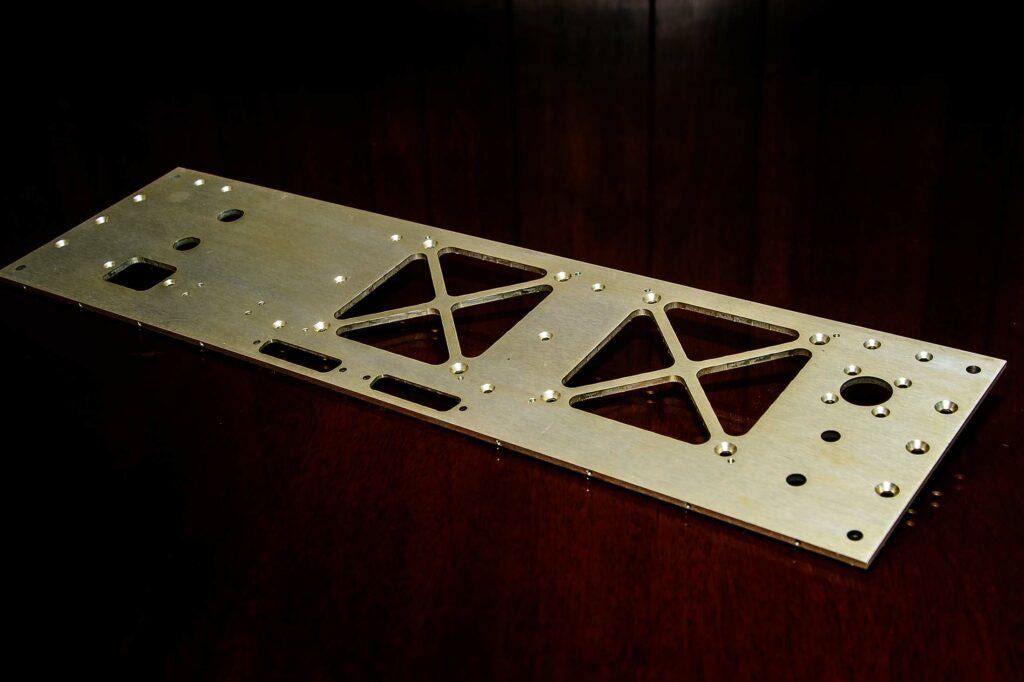 A metal plate with holes in it is sitting on a wooden table